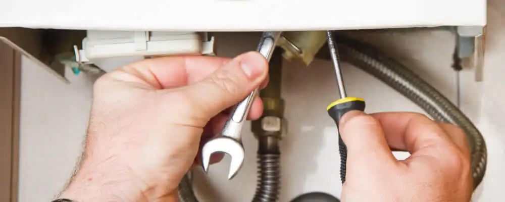 Boiler repair technician tightening pipe fittings and connections in Chico, CA