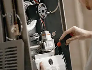 Furnace repair technician inspecting internal components and wiring in Chico, CA