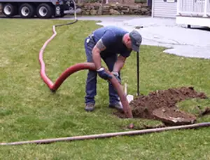 Septic pumping technician servicing a residential septic tank with a vacuum hose in Chico, CA