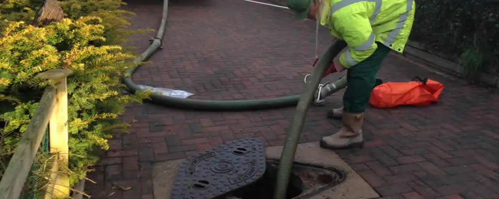 Septic tank cleaning technician servicing a septic tank with a vacuum hose in Chico, CA