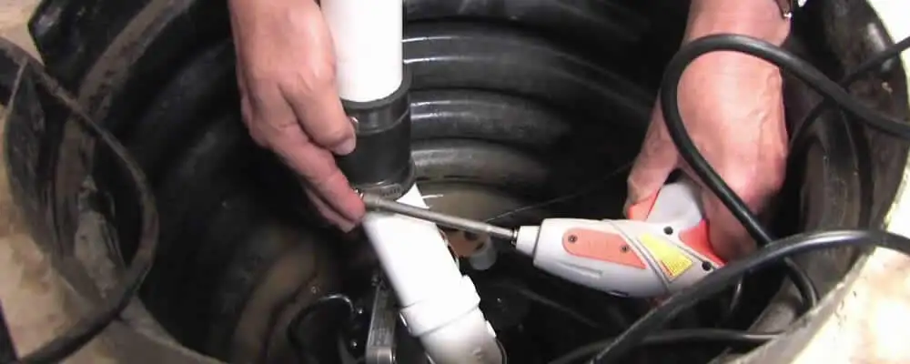 Sump pump installation technician connecting PVC discharge piping in Chico, CA